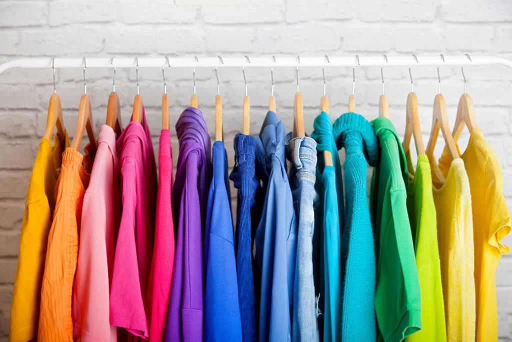 a rack of rainbow coloured clothes